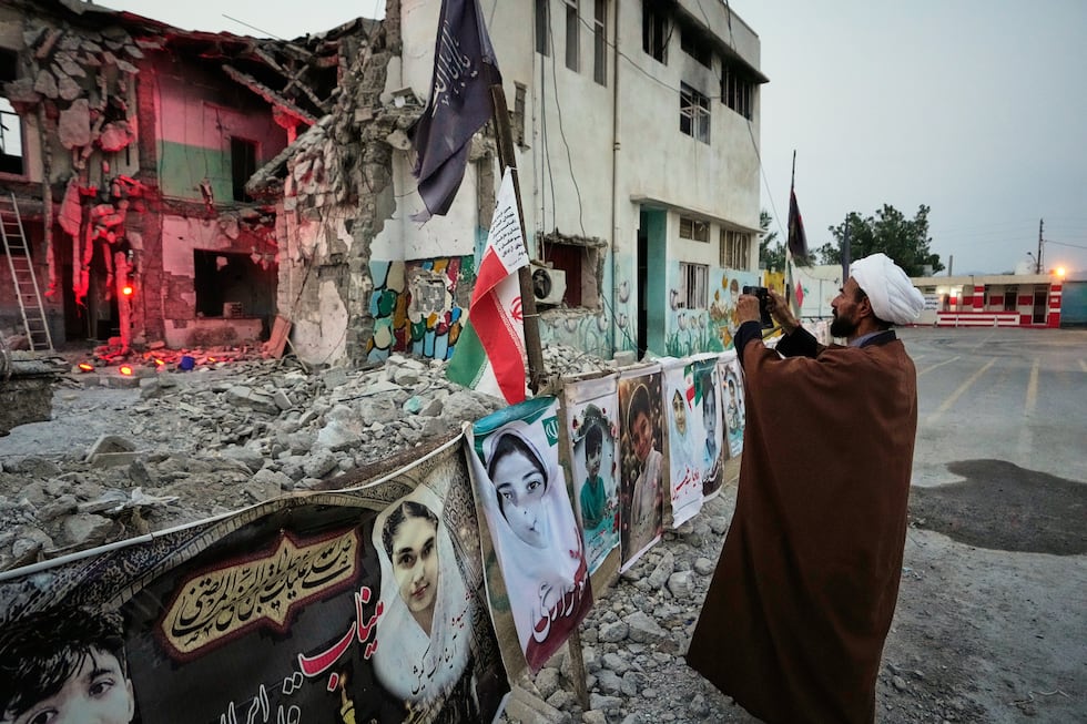 A cleric takes a photograph at the shattered Shajareh Tayyebeh school, which has become a...
